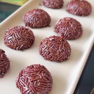 Brigadeiros sem leite prontos para serem servidos em travessa branca.